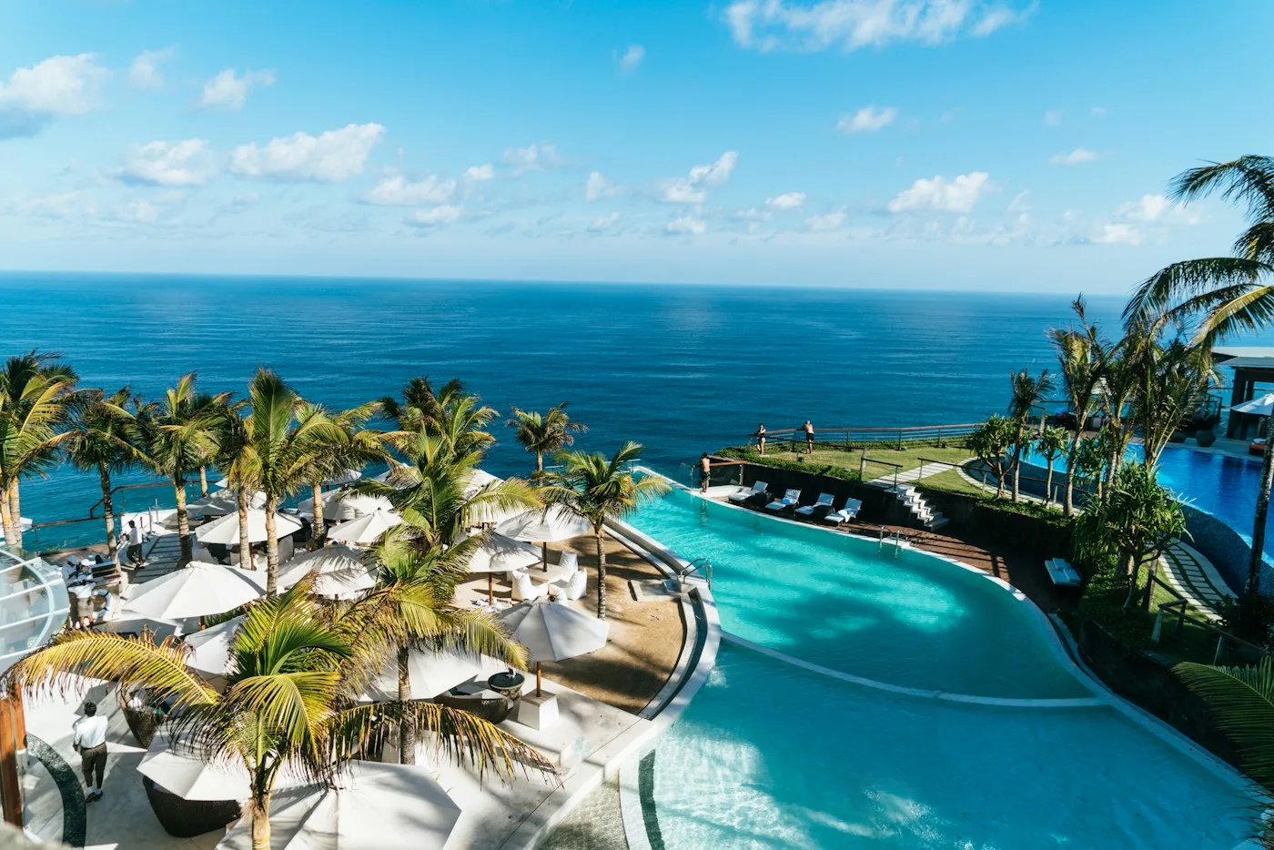 Bright turquoise resort pool framed by sun loungers and tropical landscaping