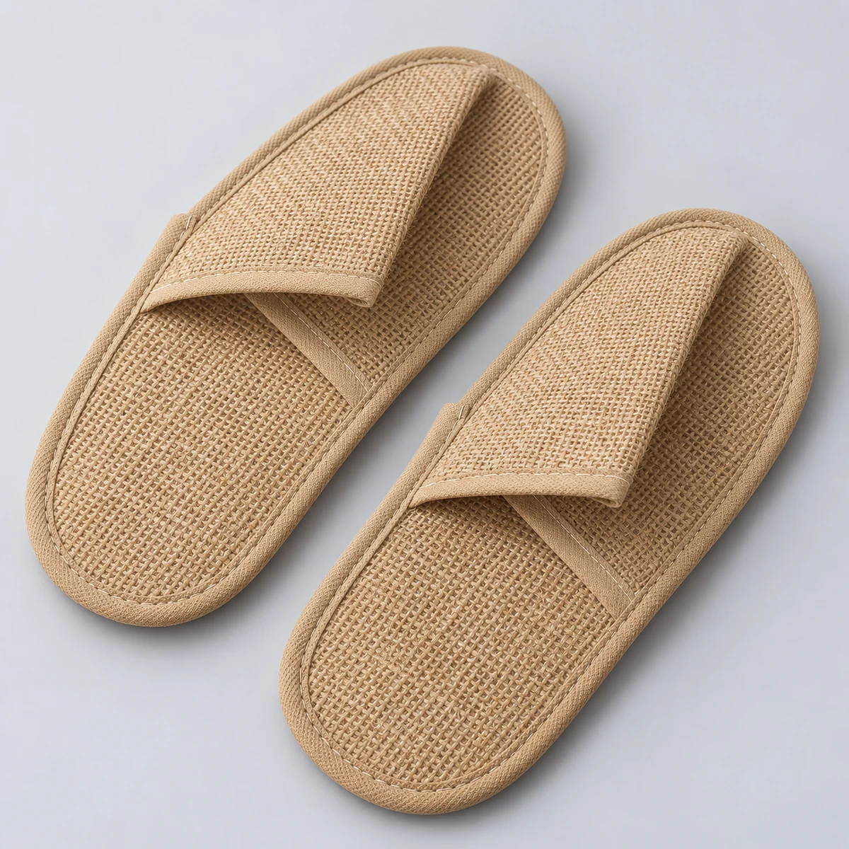 Natural jute hotel slippers with crossed fabric uppers and neatly bound edges
